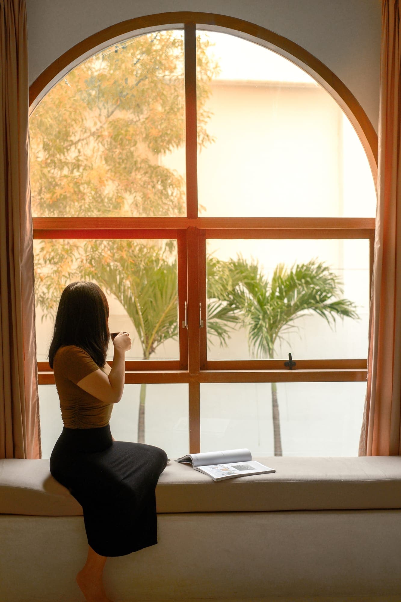 A guest with coffee at an arched window