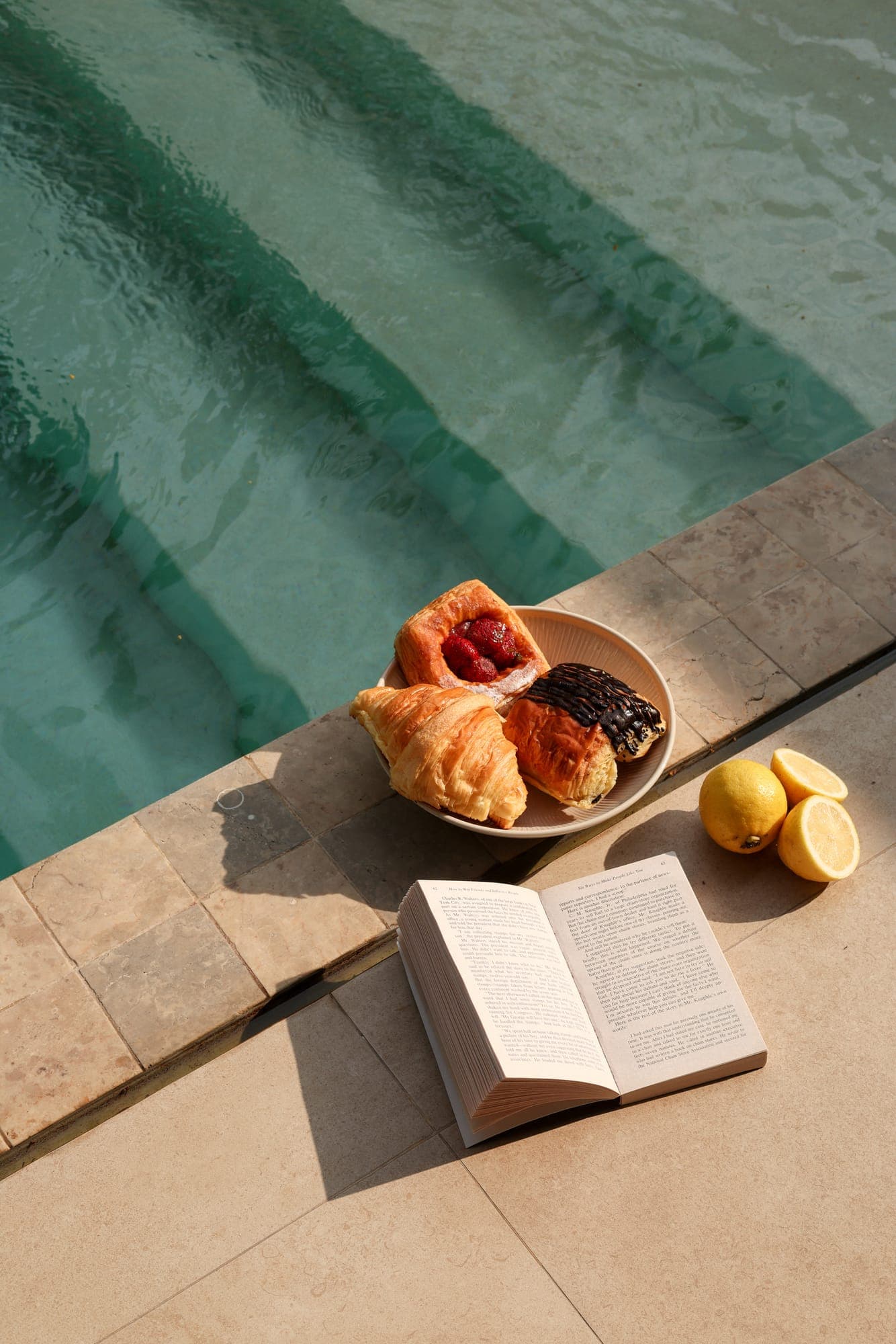 Pastries and a book by the pool