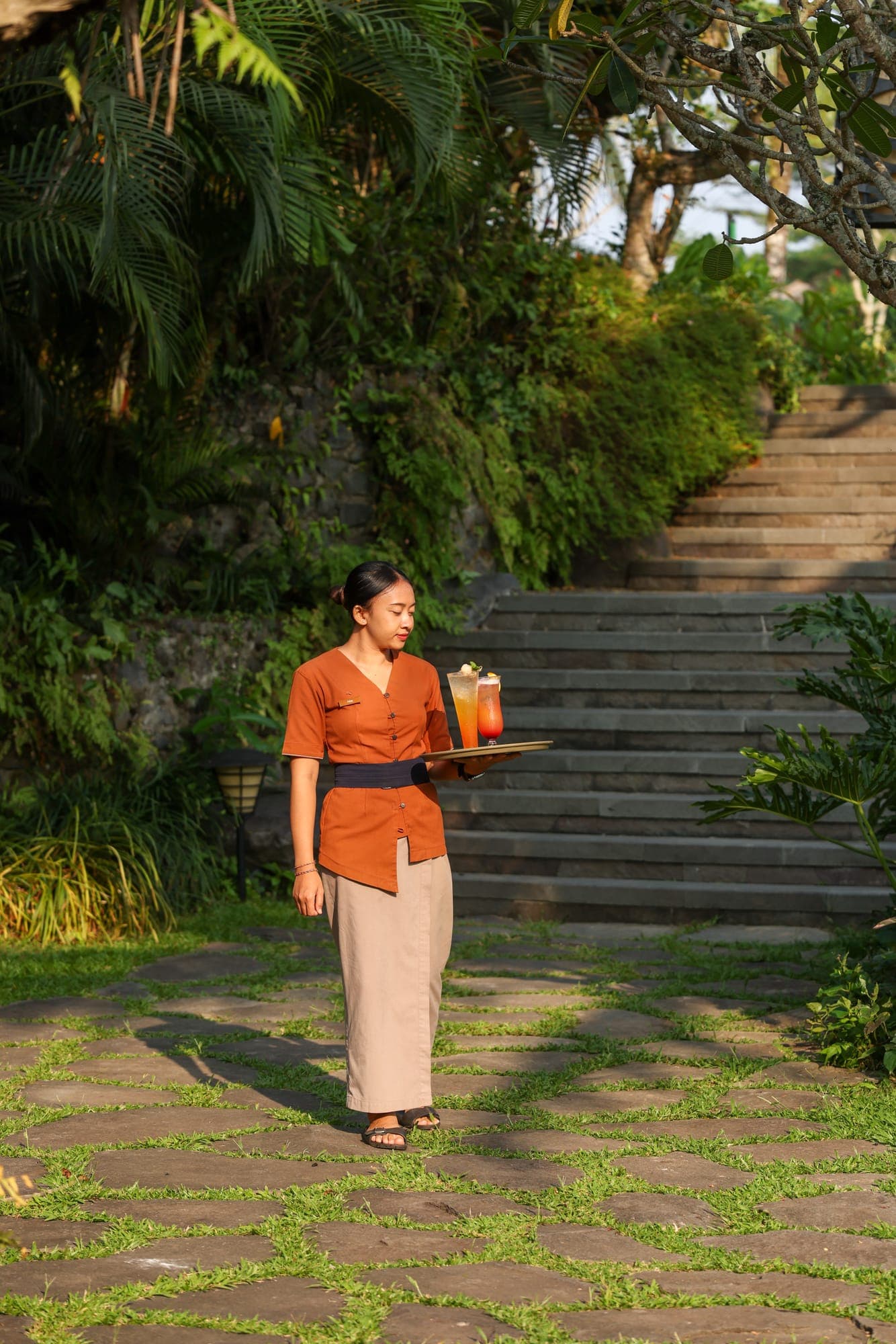 A server carrying drinks down garden stairs