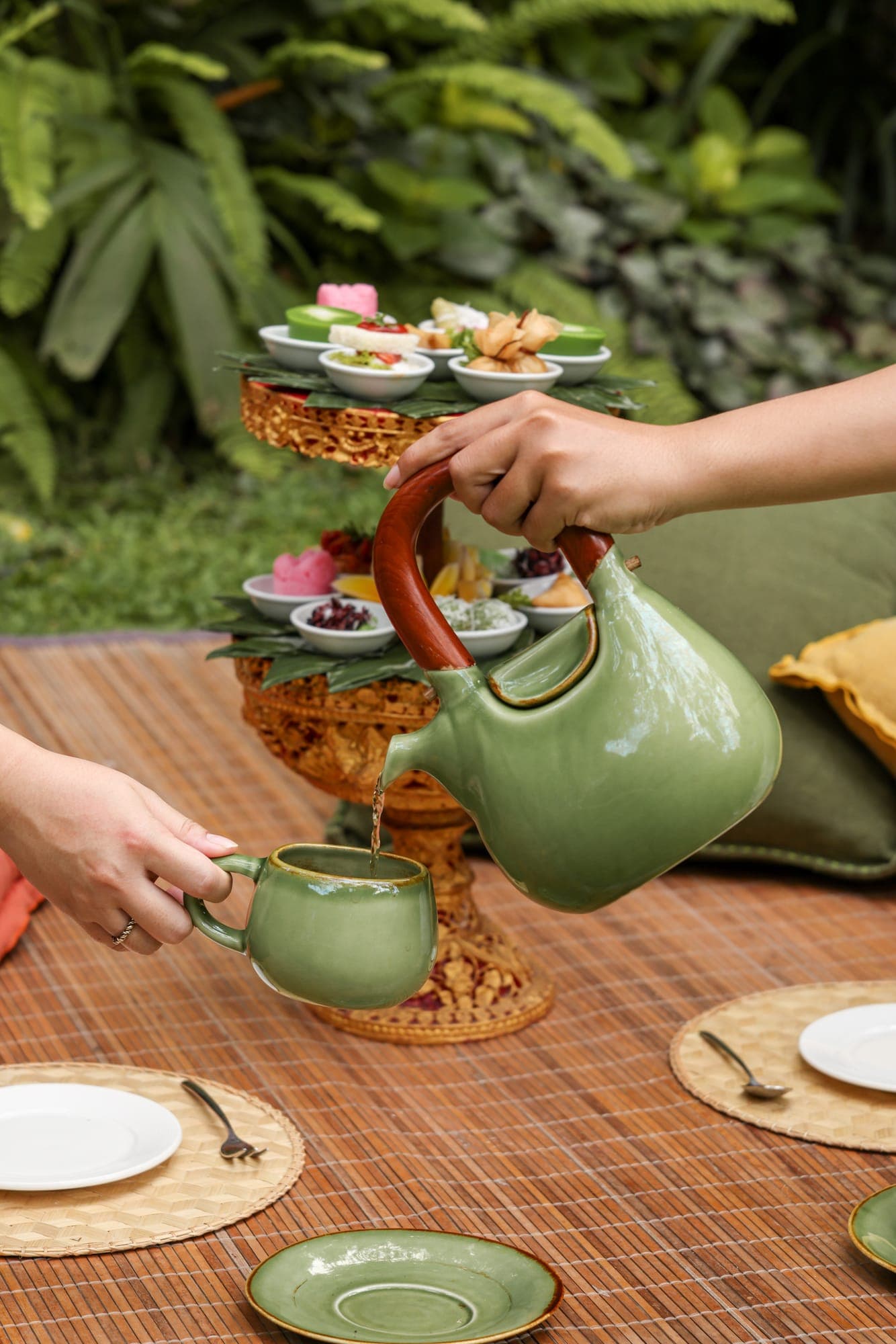 Reference: tea poured from a green teapot in a garden