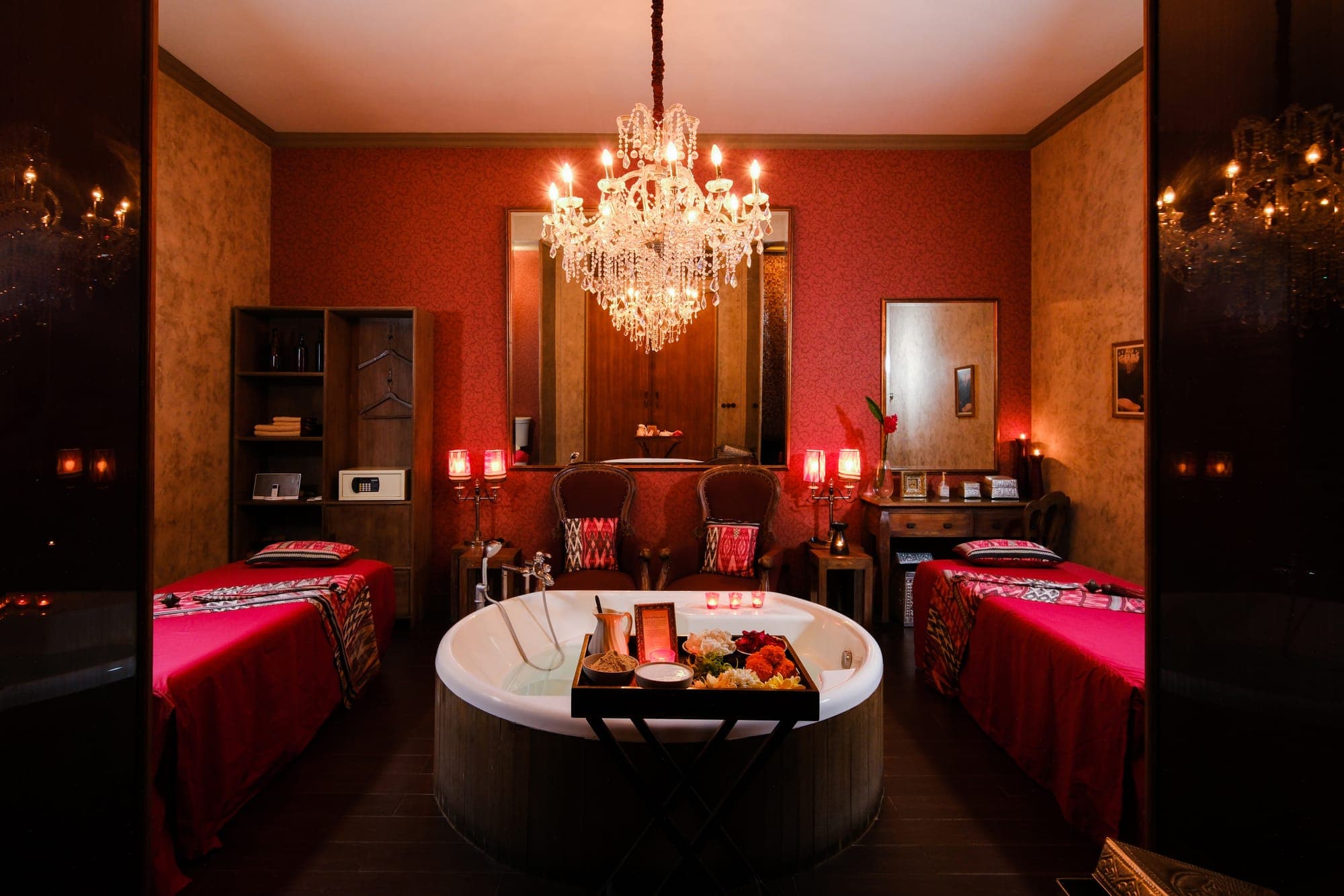 A candlelit DaLa Spa suite with a crystal chandelier, two treatment beds and a flower bath