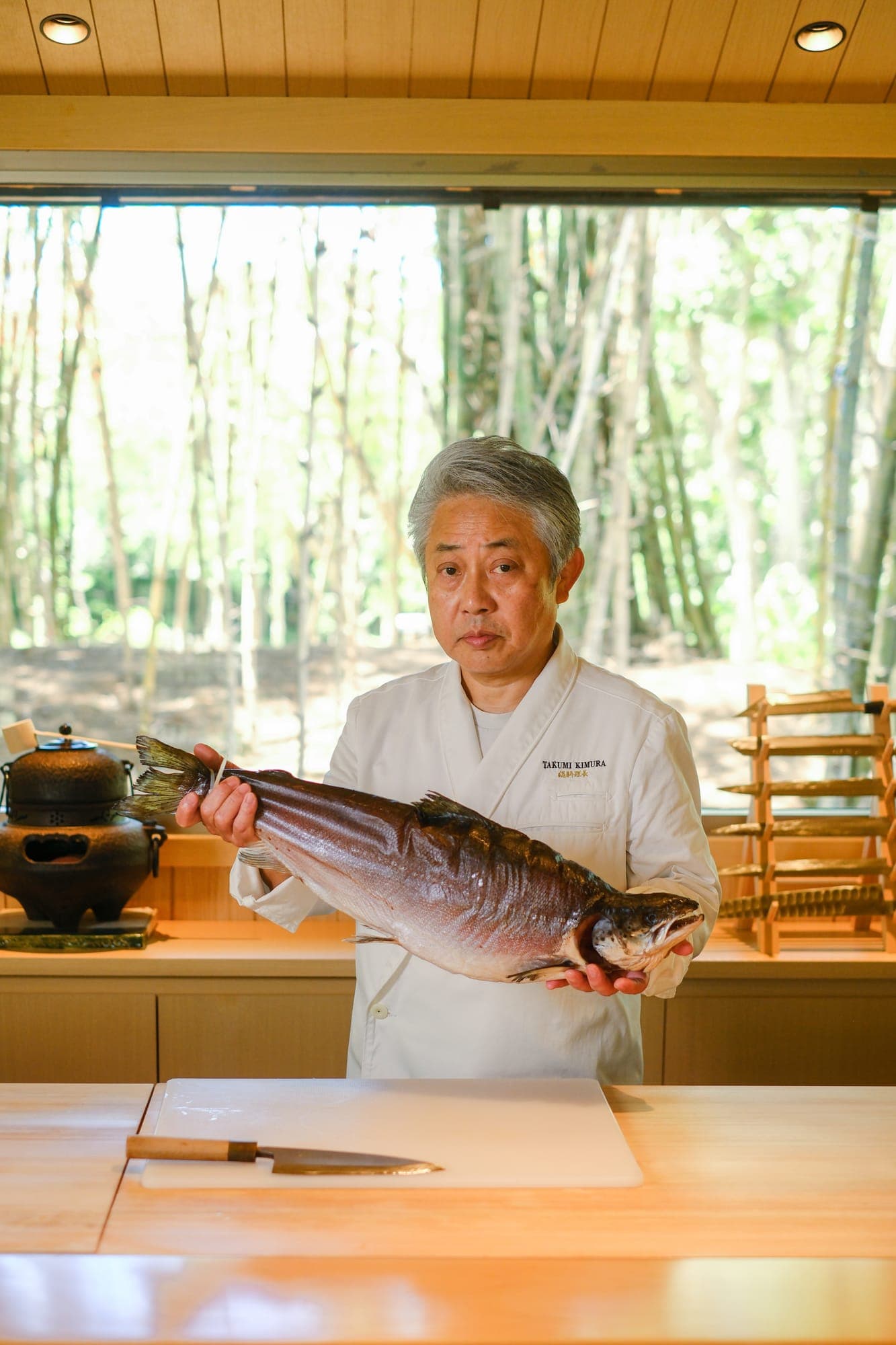 The chef holding a whole fish in the bamboo garden