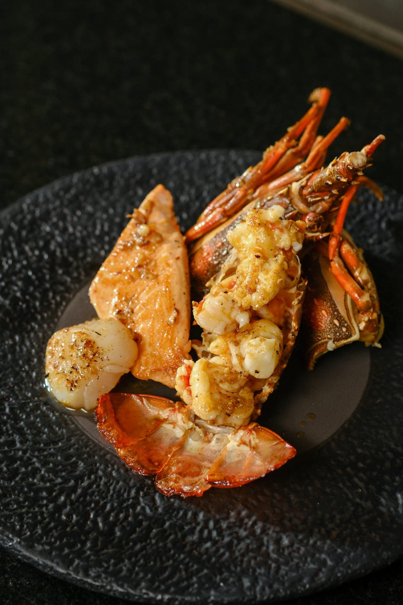 Grilled lobster glazed and served on a dark plate