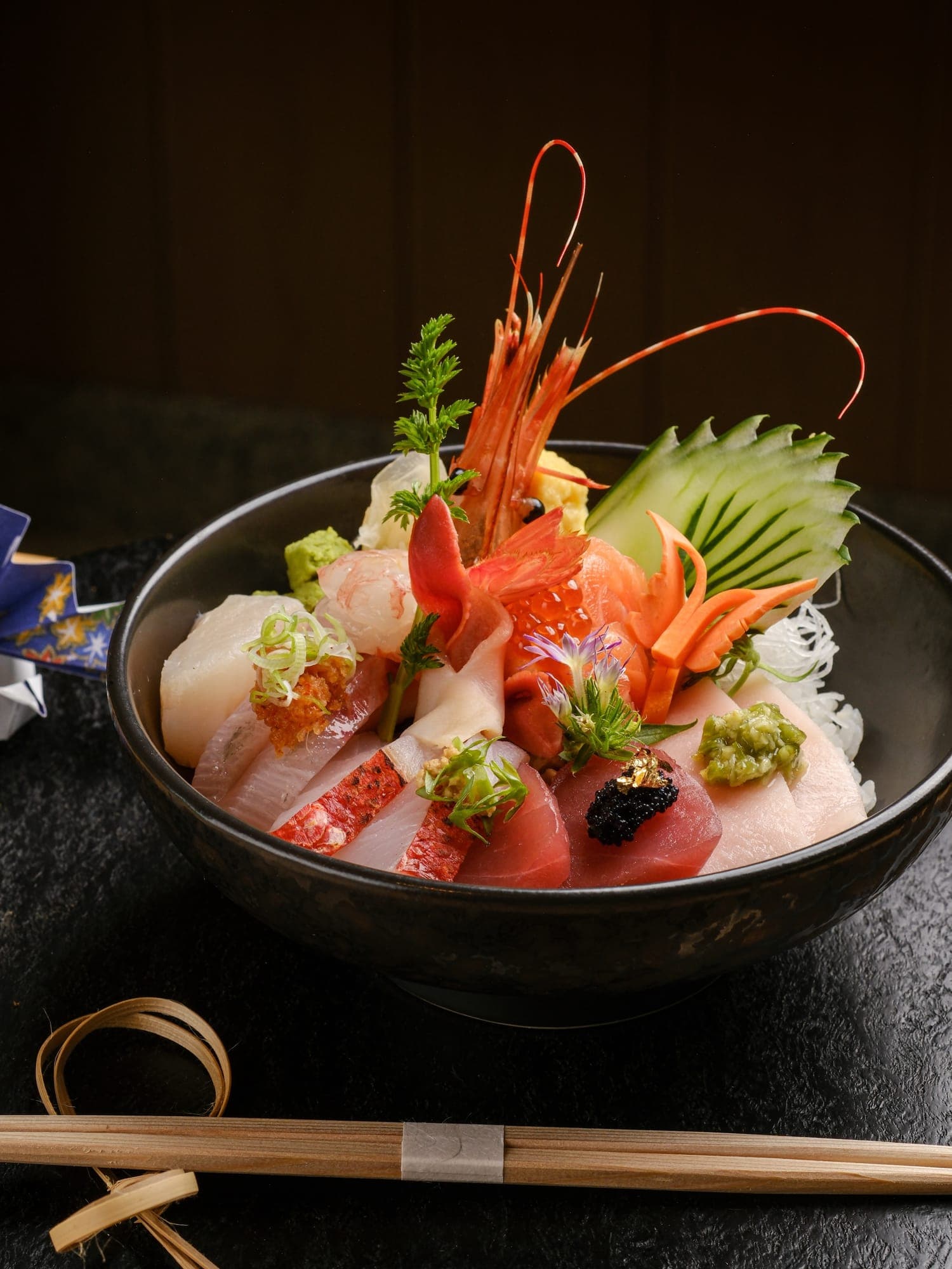 A sashimi bowl crowned with prawn and fresh garnish
