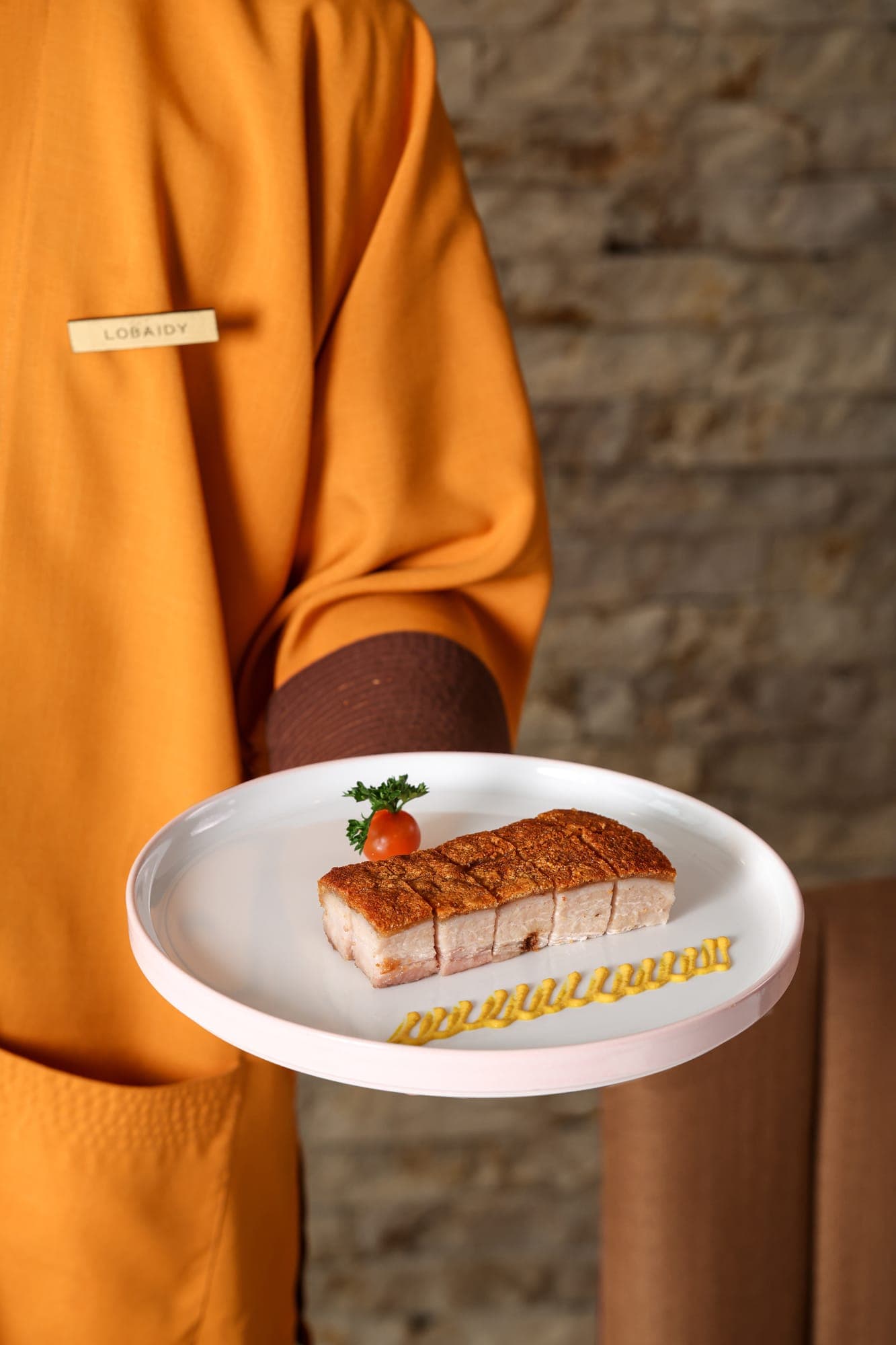 A server presenting crispy pork belly at Liu Li Palace