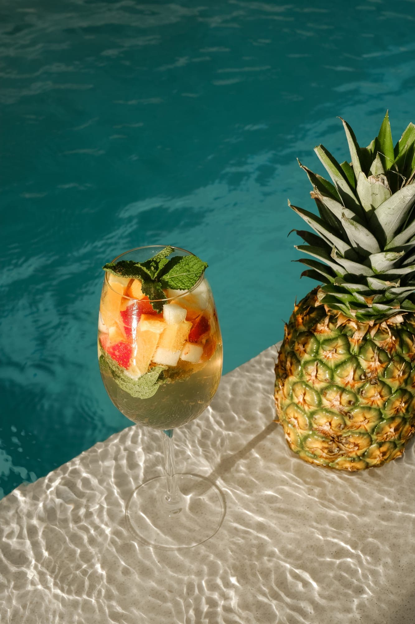 A pineapple cocktail on the edge of a villa pool