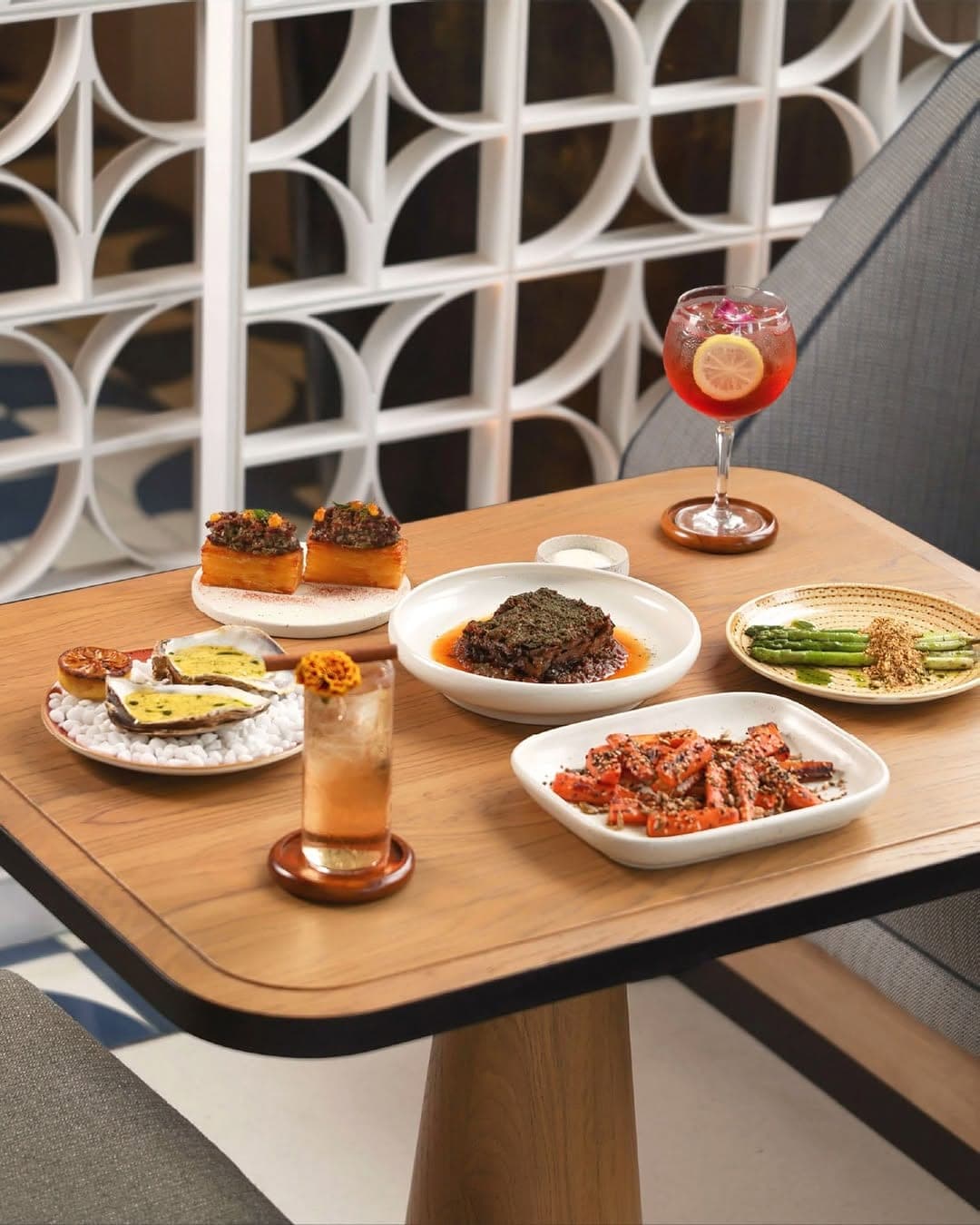 Small plates and a spritz on a table beside a breeze-block wall
